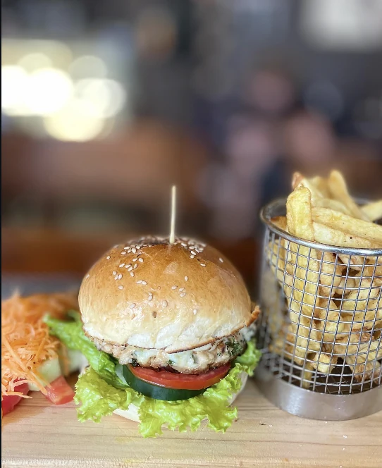A beef burger served with a basket of fries