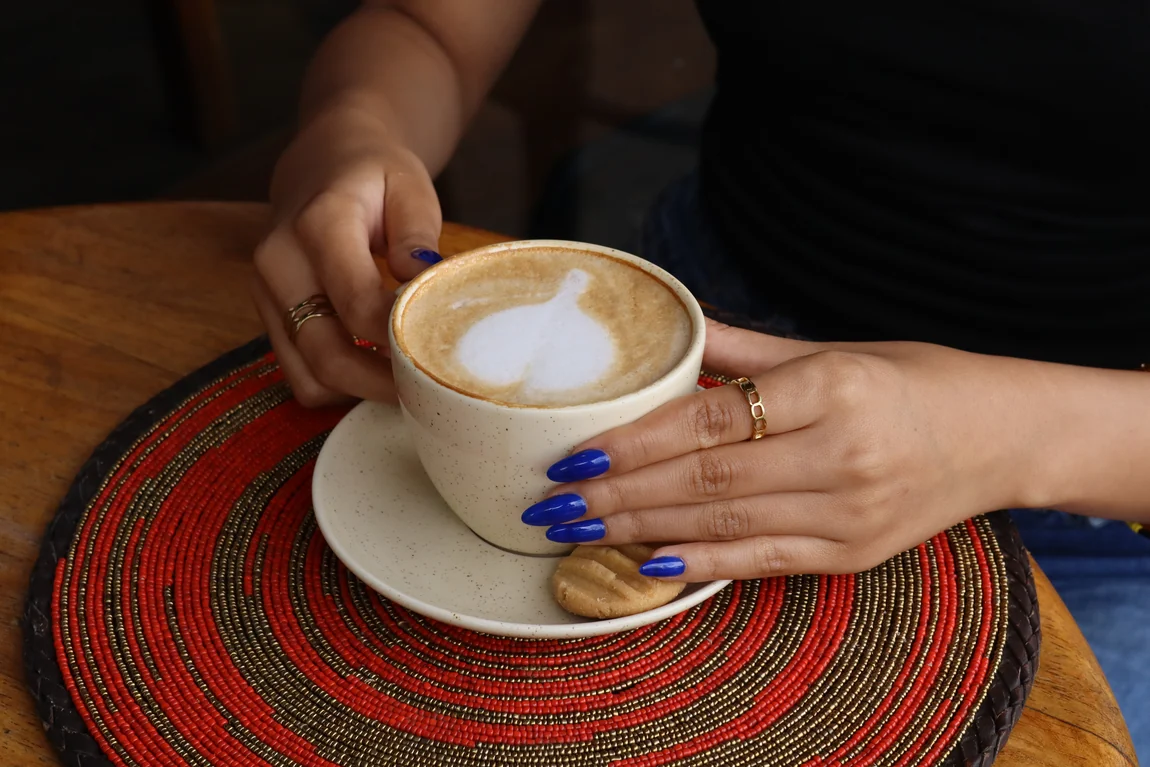 A cappuccino with latte art on a red beaded mat