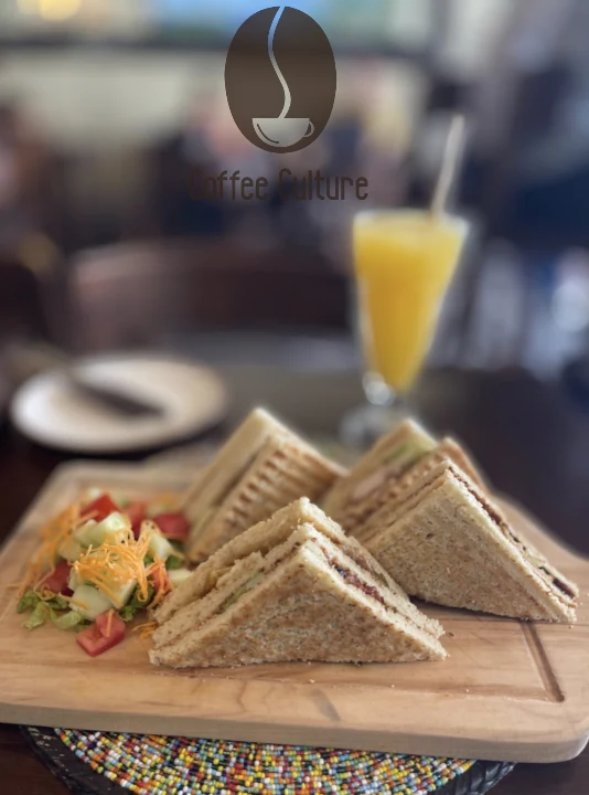 A club sandwich with a fresh juice on a wooden board
