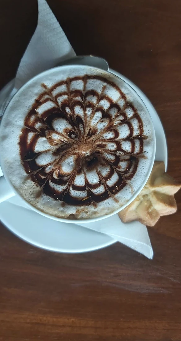 A V60 coffee with heart latte art on a wooden table