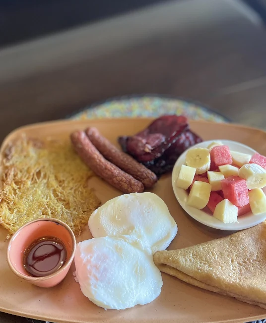 A full breakfast plate with sausage, egg, toast and fruit