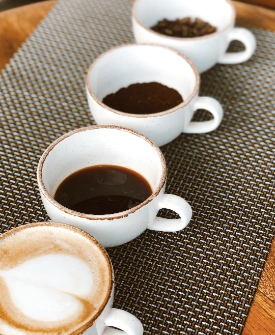A row of espresso cups freshly poured on a table setting
