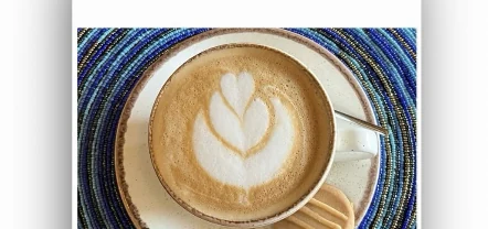 A cappuccino with heart latte art on a blue beaded mat